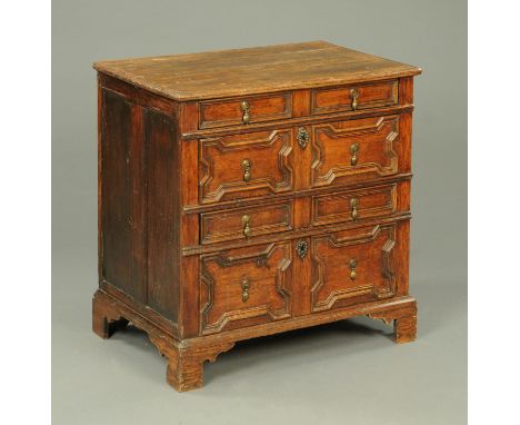An antique oak chest of drawers, four drawers with cushioned fronts and with brass drop handles and all raised on bracket fee
