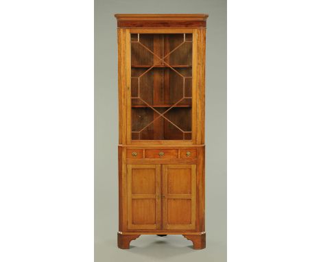 An Edwardian mahogany standing corner cupboard, with moulded cornice, glazed upper door, three frieze drawers and cupboard ba