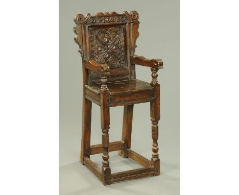 A part 17th century and later child's highchair, with carved panelled back, shaped arms, solid seat, turned legs and stretche