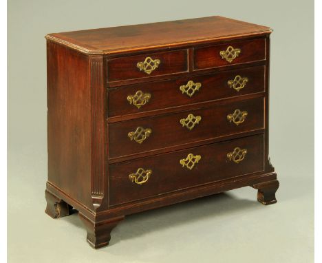 A George III mahogany chest of drawers, with two short and three long graduated drawers with canted angles and raised on ogee