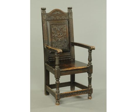 A late Victorian oak throne armchair, with carved panel back, solid seat, turned legs and stretchers.