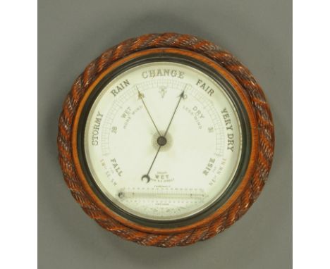 A 1930's oak aneroid barometer, circular, with rope twist edge and ceramic dial.  Diameter 28 cm. 