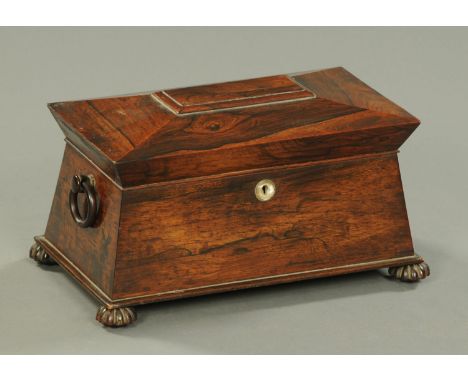A Regency rosewood sarcophagus shaped tea caddy, with two interior compartments and centre aperture, raised on lobed feet.  W