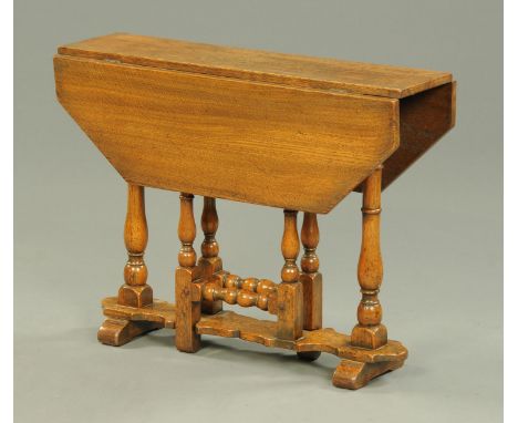 A reproduction Jacobean style small oak gate leg table, with canted angles, turned legs and low stretcher.  Length 70 cm. 