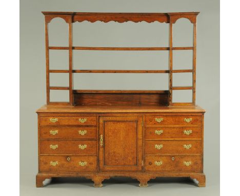 A George III oak dresser with Delft rack, with moulded cornice above a series of open shelves, the base fitted with a cupboar