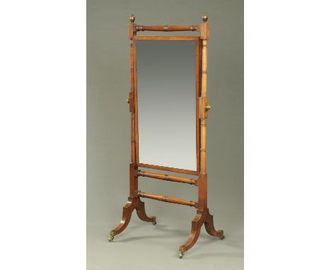 A Regency mahogany cheval mirror, the rectangular mirror set between turned columns and raised on downswept legs with brass c