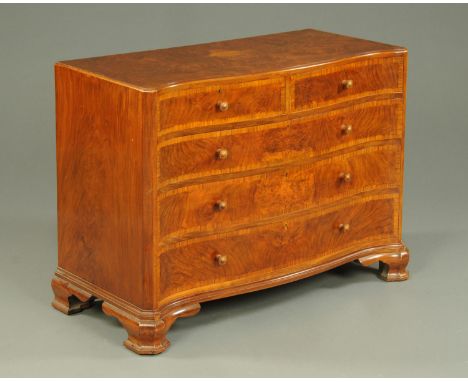 A walnut veneered serpentine chest of drawers, circa 1930, with two short and three long graduated drawers raised on ogee bra