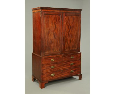 A George III mahogany linen press, with moulded cornice above a pair of doors opening to hanging space, the base fitted with 