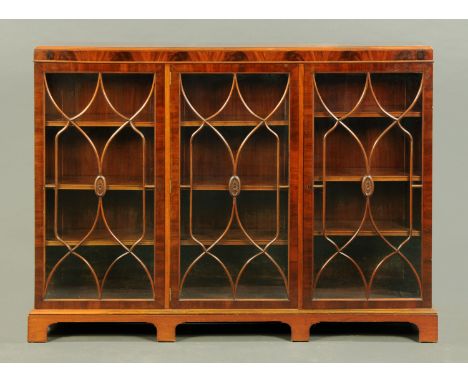 A mahogany bookcase, with caddy top and three glazed doors with shaped wooden astragals enclosing adjustable shelves and rais