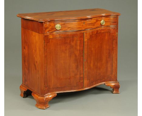 A George III mahogany serpentine fronted side cabinet, with single drawer above a pair of panelled cupboard doors enclosing s