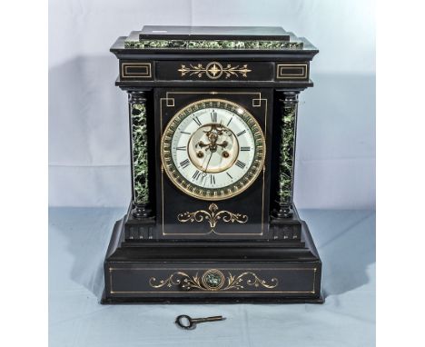 A small Victorian black slate and marble mantel clock with white enamel face and visible escapement.  In good working order. 