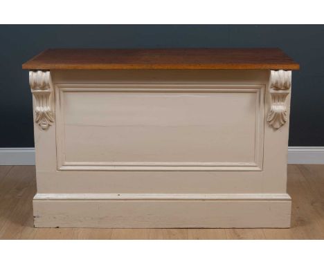 A shop or kitchen counter, with hardwood top, the painted base with panneled front and decorative scrolls, open at the back, 