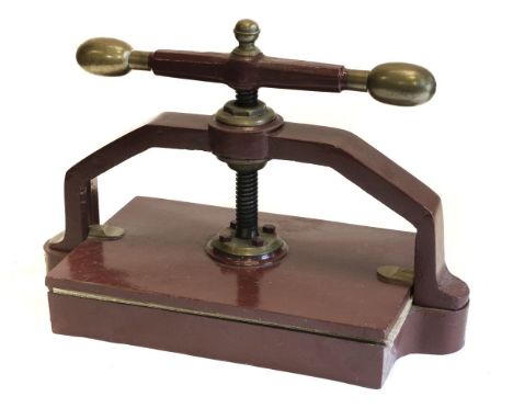 * Bookpress. A cast iron bookpress, finished in red, with brass handle ends &amp; finial, platen approximately 45.5 x 30 cm (