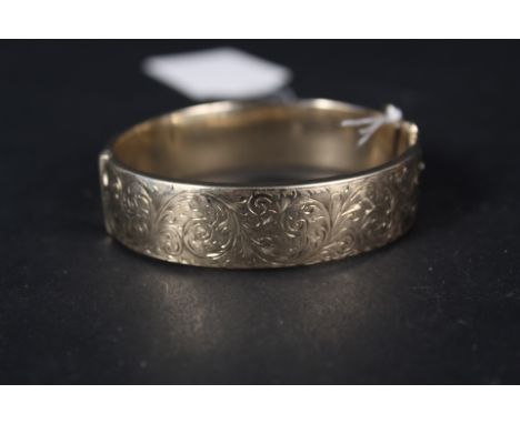 A wide 9ct gold foliate engraved bangle (lacking safety chain)