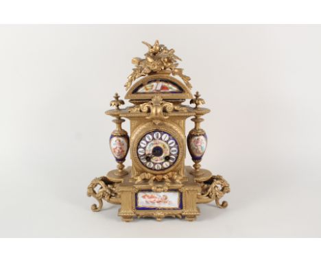 A 19th Century French gilt metal striking mantel clock with bird and leaf crest, porcelain cherub and musical trophies decora