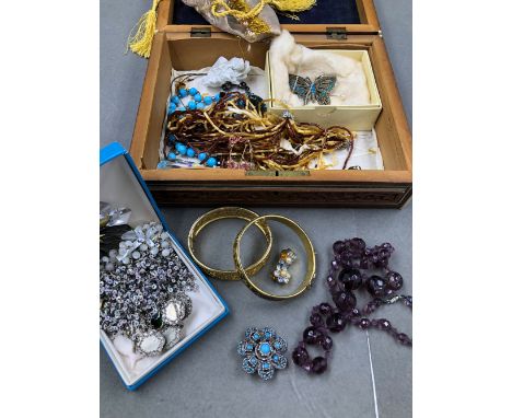 A COLLECTION OF VINTAGE COSTUME JEWELLERY TO INCLUDE BANGLES, BROOCHES, EARRINGS, FACETED AMETHYST BEADS, A ROSARY ETC CONTAI