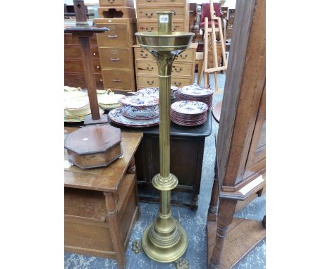 A BRASS FLOOR STANDING CANDLESTICK ON THREE PAW FEET