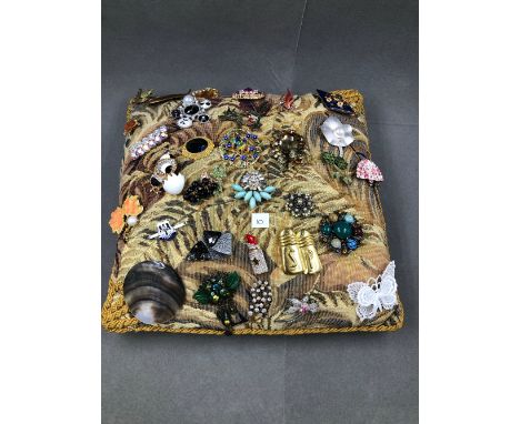 AN ASSORTED COLLECTION OF BROOCHES DISPLAYED ON A VINTAGE WOVEN CUSHION. TOTAL NUMBER OF BROOCHES 21. 