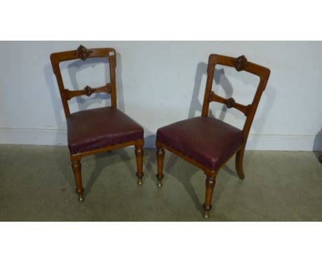 A pair of Victorian oak aesthetic movement side chairs with leather seats and front roller casters 