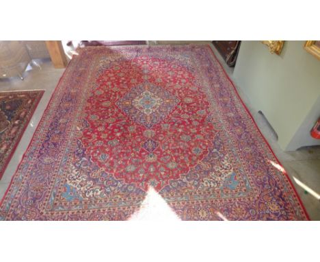 A large red ground hand knotted woollen rug with stylized floral decoration and central medallion 410 cm x 295 cm 
Condition 
