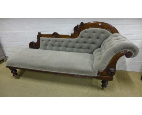 A Victorian carved walnut scroll button back chaise longue - upholstered in green velour - Height 91 cm x Length 184 cm
