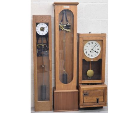 Longcase electric master clock, the 6.5" white dial enclosing a skeletonised centre, within an oak glazed case, 55" high (wit