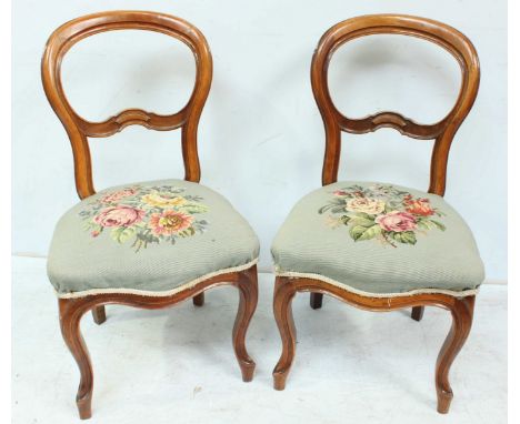 A pair of Victorian stained walnut balloon back standard chairs with floral tapestry seats on cabriole front supports 