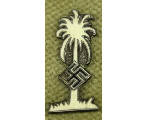 A WWII German DAK Afrika Korps palm tree label pin, in white enamel on white metal, the back with stamped mark RZM, and Ges. 