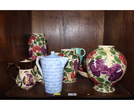 SECTION 53. A shelf of assorted Wade pottery jugs and vases, decorated with flowers and leaves.