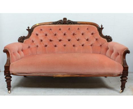 A Victorian carved walnut button back settee, with foliate carved show wood frame, pink velvet upholstery and supported on tu