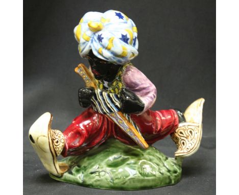 A late 19th early 20th century pottery figure of Turkish boy wearing a turban with sword strapped to his chest whilst running