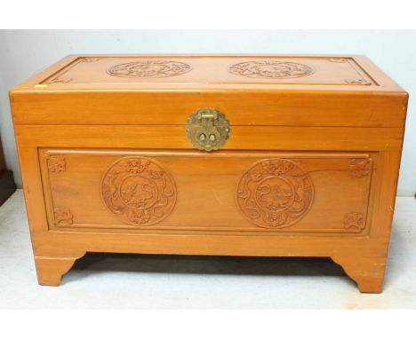 A large mid 20th century Chinese carved camphor wood trunk, carved with dogs of foe and motifs. 101 cm wide.