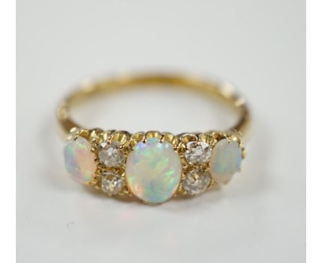 A yellow metal (tests as 18ct), three stone white opal and four stone diamond set half hoop ring, size N/O, gross weight 3.5 