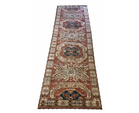 FINE KAZAK RUNNER, 260cm x 83cm, row of stylised floral medallions on a ruby field within a complimentary border. 