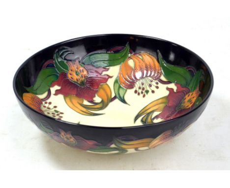 MOORCROFT; a navy and cream ground 'Anna Lily' pattern tubeline decorated footed bowl with impressed marks and year cipher fo