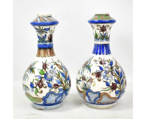 A pair of circa 1900 Persian ceramic bottle vases painted in underglaze with floral sprays and decorative bands, height 29.5c