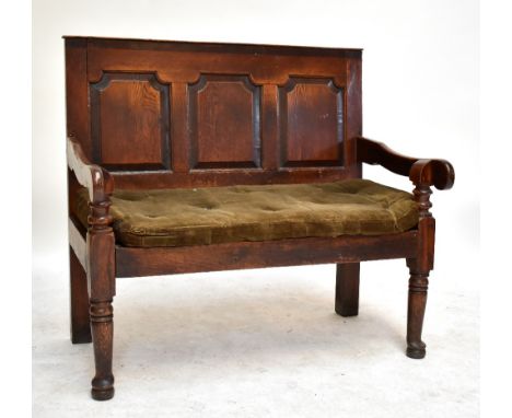 A George III and later oak settle, with panelled back and raised on ring turned supports, now with padded corduroy seat, leng