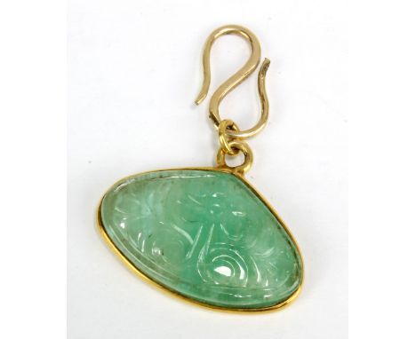 A carved jade lozenge shaped pendant suspended in yellow metal mount, width 2.5cm.
