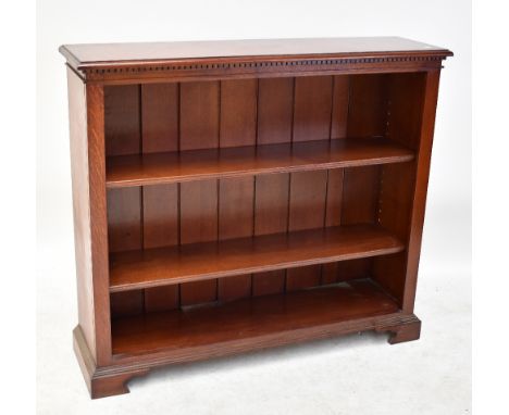 A reproduction oak bookcase with dentil carved detail and two shelves on bracket feet, 99 x 122cm.