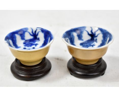 A pair of 19th century miniature cafe-au-lait glazed bowls, the interiors painted in underglaze blue with carp, each bearing 