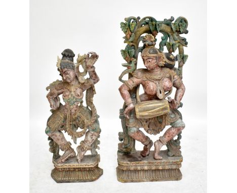 A 20th century Indian polychromed carved wooden flatback figure of Hindu female deity playing drum on foliate scroll and foli
