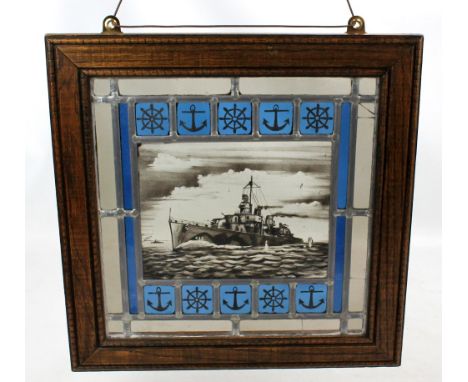 An oak framed stained glass panel painted with gunship to centre and maritime symbols, 42.5 x 41.5cm including frame.&nbsp;Ad