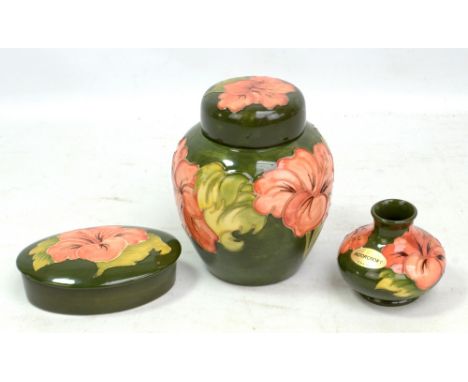 MOORCROFT; a green ground 'Hibiscus' pattern tubeline decorated ginger jar, height 15.3cm, lidded dish and small vase, all wi