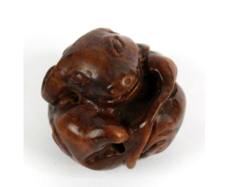 A late 19th/early 20th century Japanese carved wooden sphere modelled as an entwined ox, later adapted to a netsuke, diameter