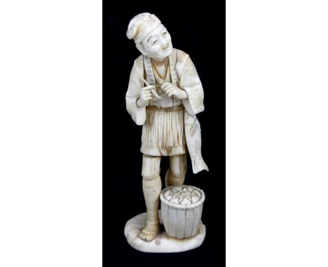 A Japanese Meiji period carved ivory okimono of a gentleman holding a pipe with a fish and a basket, signed to base, height 2