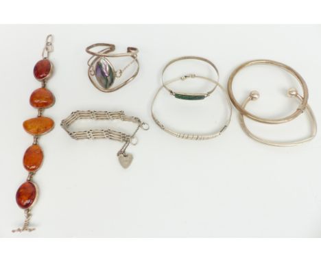 Five silver bangles, a silver gate bracelet and a pressed amber bracelet&nbsp;