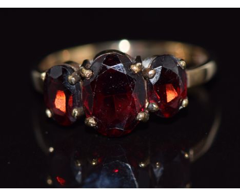 A 9ct gold ring set with three oval cut garnets, 2g, size K