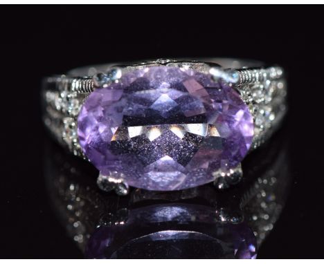 A 9k white gold ring set with an oval cut amethyst and diamonds to the shoulders and mount, 5.9g, size M/N