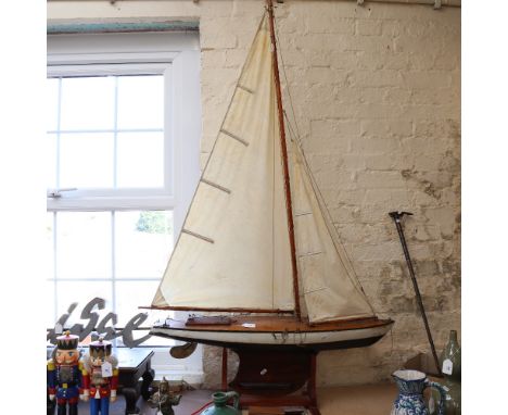 A large 19th century black and white lacquered wooden-hulled model pond yacht, with sails and rigging, hull length 94cm, on w