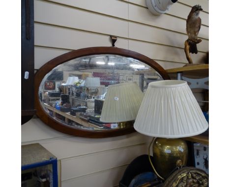 An early 20th century inlaid satinwood oval bevelled-edge wall mirror, 84cm x 46cm and a brass hammered design table lamp (2)